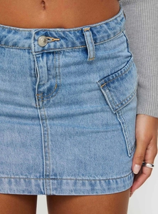 Vue détaillée d'une mini-jupe en jean bleu délavé avec poche cargo et surpiqûres