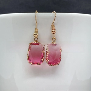 Macro detail of faceted pink rectangular crystal drop earrings with golden ear hooks