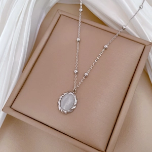 Detailed view of silver titanium steel necklace with white opal pendant on jewelry box