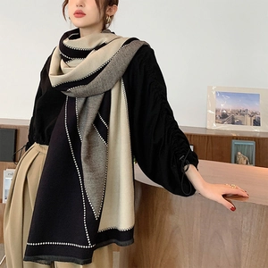 Detail view of the thick knit texture and stitched geometric patchwork pattern on the scarf