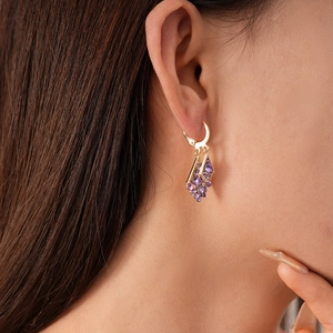 Close-up of vintage geometric gold earrings with purple zircon stones on model