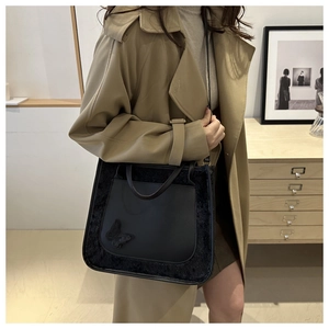 Détail du sac cabas en similicuir noir avec bordure en peluche et papillon 3D