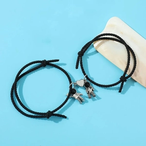 Detailed view of black magnetic couple bracelets with astronaut charms and heart magnets