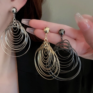 Macro shot showing metallic texture of gold, silver, and black layered hoop earrings