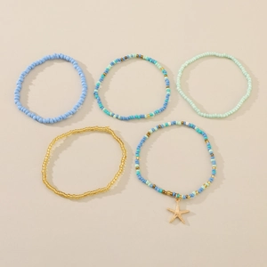 Detail of 5-piece bohemian beaded anklets set with blue beads and golden starfish charm