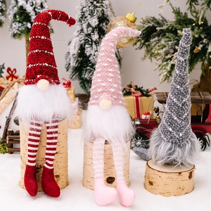 Three knitted Christmas gnomes with striped long legs displayed in a festive holiday scene