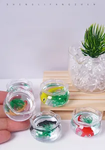 Macro shot of miniature koi fish tank model featuring colorful resin fish and green plants