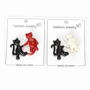 Detail view of cute enamel cat brooches in black, red, and white on fashion display card