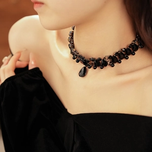Close-up of vintage-style necklace with drop-shaped black gemstones and pearls on model