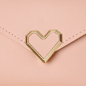 Detailed close-up of pink leather wallet featuring a golden heart metal buckle
