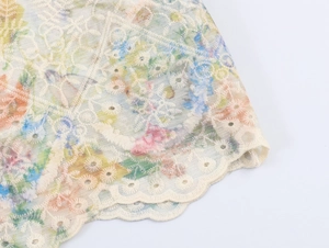 Detailed macro view of sheer floral fabric with delicate lace embroidery and scalloped edges