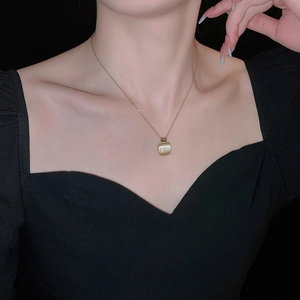 Gros plan d'un collier carré en œil de chat en acier titane doré porté par un mannequin