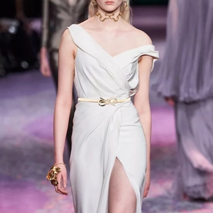 Detail of a gold elastic spring belt with a bow buckle on a white dress