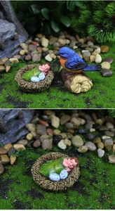 Détail d'un bébé fée endormi et d'une figurine d'oiseau dans un micro-paysage de jardin en résine