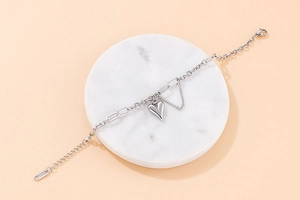 Macro shot of silver heart pendant bracelet on marble tray with mixed chain link detail