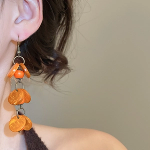 Détail de boucles d'oreilles vintage orange avec perles géométriques en noix de coco et franges