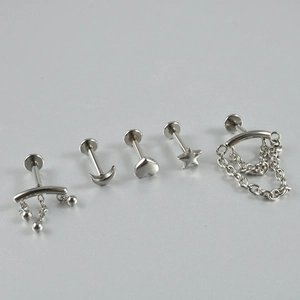 Détail de bijoux de piercing en acier argenté avec formes de lune, cœur et étoile