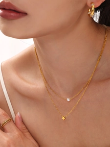 Detail of layered gold titanium necklace with pearl and star pendants on model