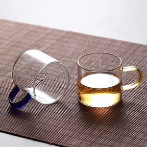 Heat-resistant borosilicate glass tea cups with blue and yellow handles on bamboo mat