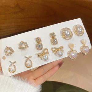 Detail of 6 pairs of gold earrings set featuring pearls, rhinestones, and elegant shapes