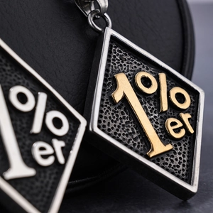 Makroansicht der Vintage 1%er rautenförmigen Metallanhänger auf dunklem Leder