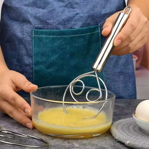 Action shot of hand using a stainless steel whisk to mix eggs in a glass kitchen bowl