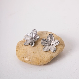 Silver flower-shaped stud earrings with brushed metal texture on a white background