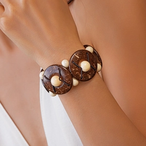 Gros plan d'un bracelet élastique en perles de coco et bois sur un poignet féminin