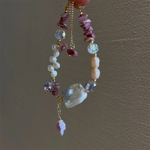 Handheld view of baroque pearl bracelet with pink rose stones and gold chain