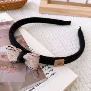 Detail showing knit bow headband with beige stripes and brown leather bunny ornament