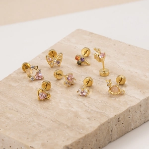 Golden butterfly and heart stud earrings with pink zircon on a stone stand