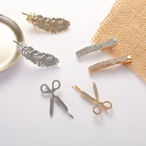 Detailed view of alloy hair clips with sparkling rhinestones in feather and scissors shapes