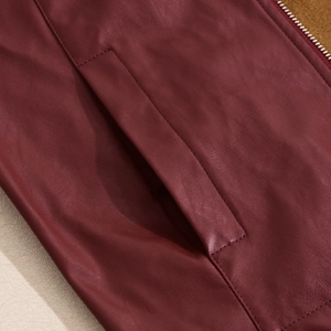 Detailed macro view of stitching and side pocket on a slim-fit burgundy PU leather jacket