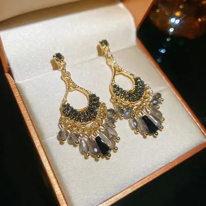 Vintage gold and black tassel earrings with geometric charms in a jewelry box