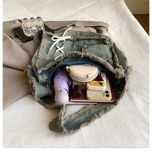 Detail view of large capacity washed denim tote bag with frayed edges and lace-up design