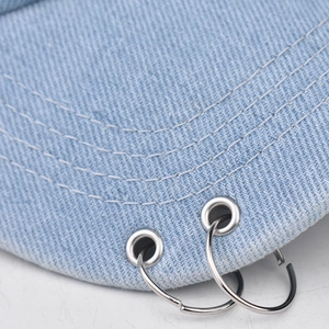 Close-up of light blue washed denim cap featuring metal rings and reinforced stitching
