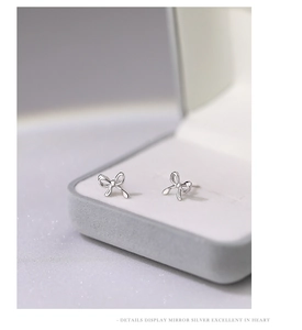 Macro shot of mirror-polished S999 silver bow earrings in a luxury jewelry box