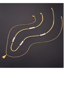 Détail d'un collier double épaisseur doré avec pendentif cœur et perles d'eau douce