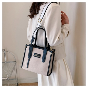 Detail of canvas tote bag with contrast black trim and striped wide shoulder strap
