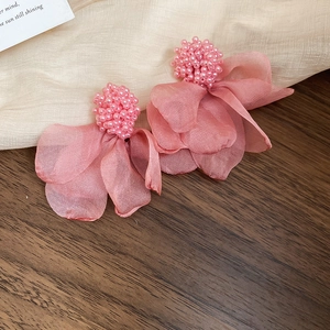 Close-up of pink fabric flower earrings with faux pearls on soft tulle background