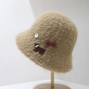 Détail d'un chapeau cloche en maille camel avec écusson de chien et nœud à carreaux
