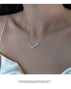Detailed close-up of a silver V-shaped necklace with elegant pearls and zircon inlay
