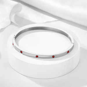 Detailed view of silver screw bangle with red zircon stones and 18k gold plating
