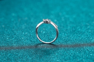 Macro shot of V-shaped S925 silver ring with moissanite center stone on glitter background