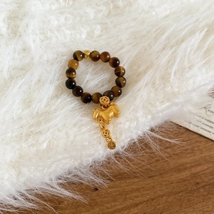 Detailed macro view of tiger eye bead ring featuring a gold horse and coin charms