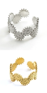 Detail view of gold and silver gear-shaped adjustable stainless steel rings on white background