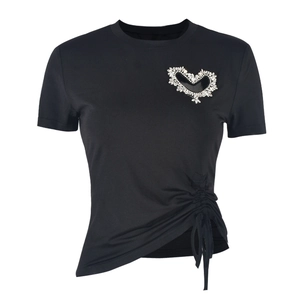 Détail d'un t-shirt noir avec motif cœur en strass et cordons de serrage latéraux