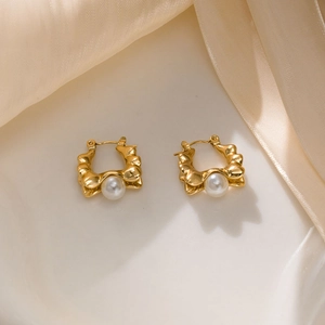 Close-up of vintage gold wave earrings featuring elegant white pearls and texture