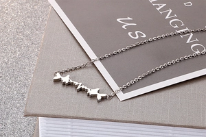 Macro shot of silver titanium heartbeat fish pendant necklace on a grey book cover