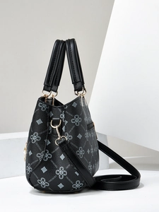 Detail of black leather handbag with geometric monogram print and gold-tone metal hardware